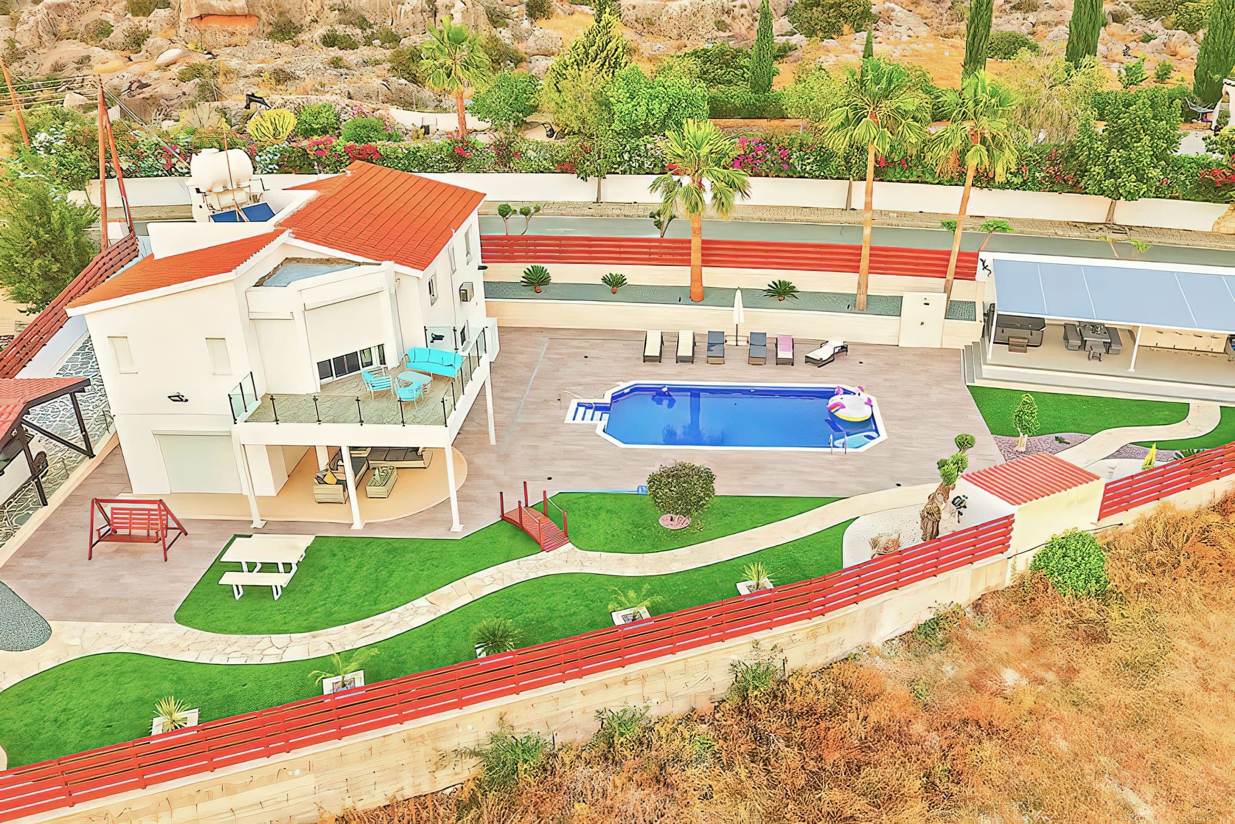 Aerial view of Villa Prasino with its pool, landscaped gardens and covered games area in Peyia