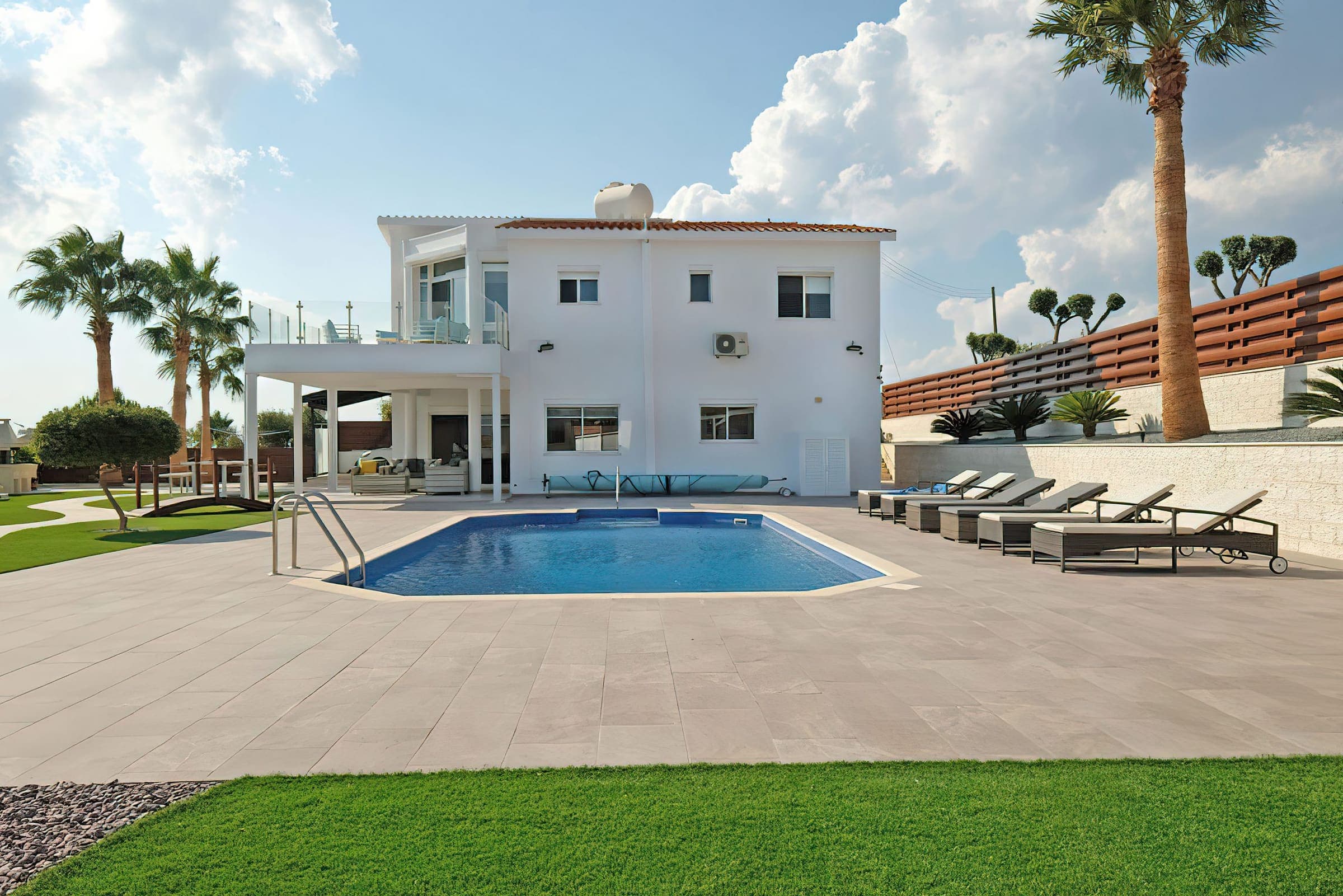 The white two-storey villa behind the pool and sun loungers