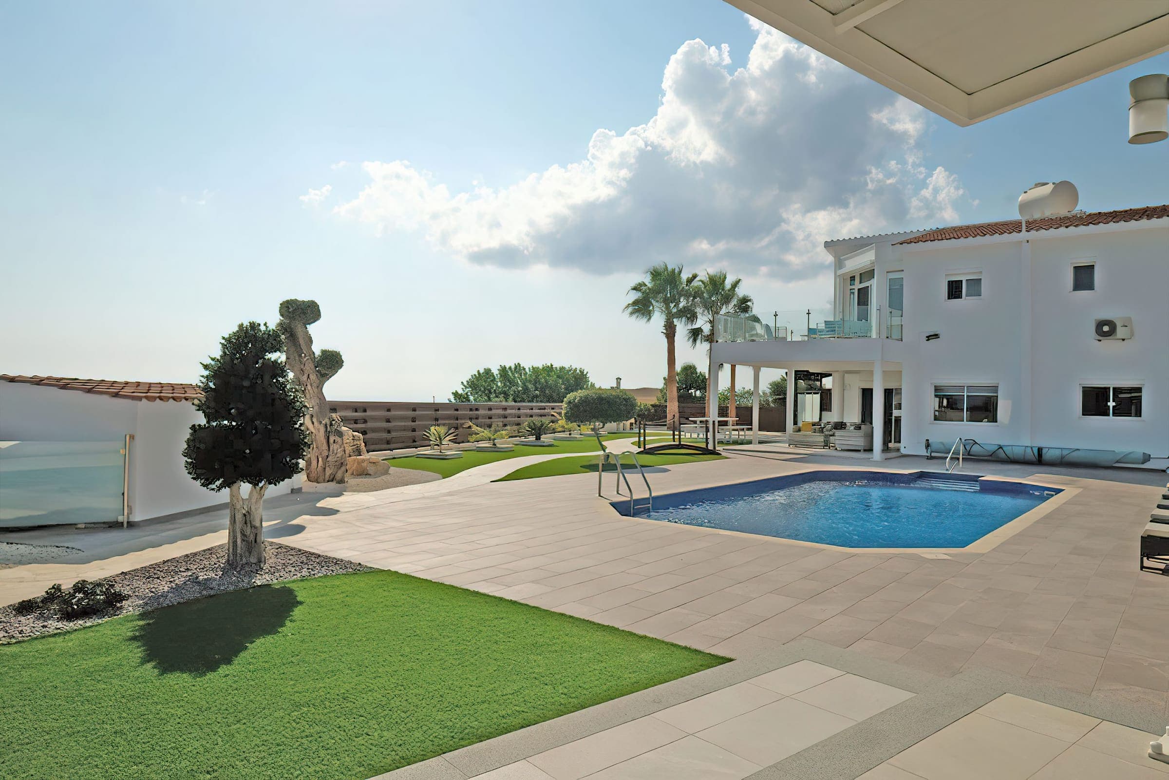 Villa exterior with pool, lawn and a mature olive tree