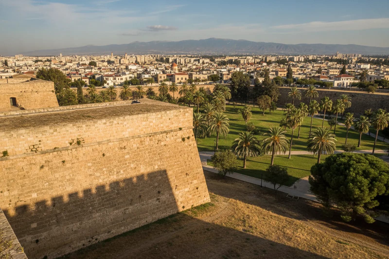 Un bastione veneziano in pietra delle mura della città vecchia di Nicosia sopra un fossato a giardini, con i tetti oltre