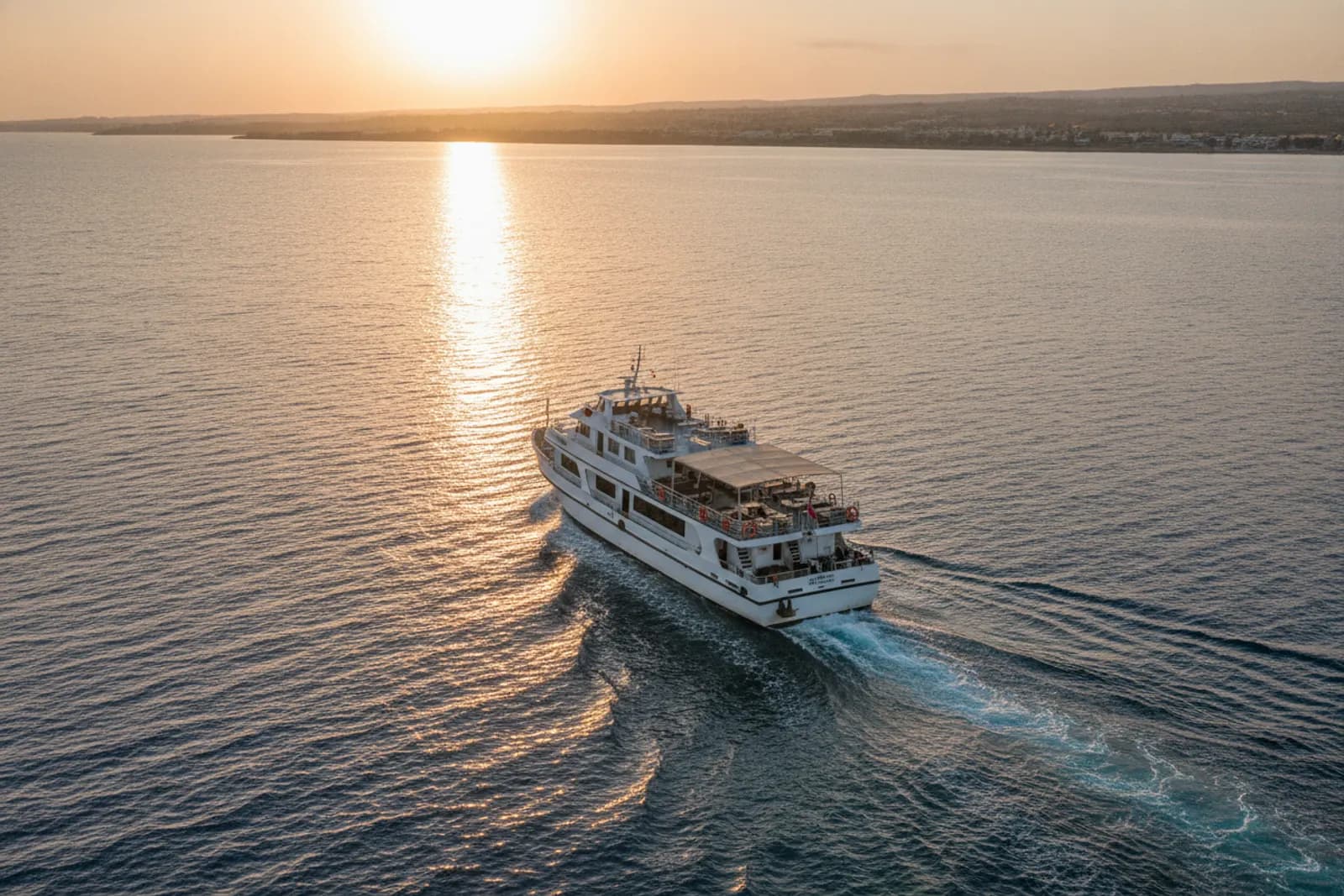 Barca da crociera bianca sul mare calmo al tramonto, al largo di Paphos, con una calda scia di luce sull’acqua