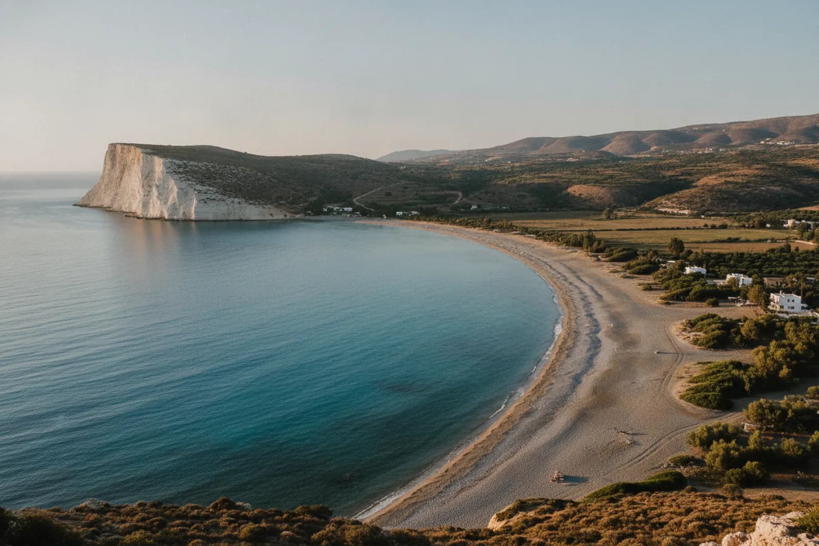 La lunga spiaggia curva della baia di Pissouri, a Cipro, con le scogliere chiare di Capo Aspro all’estremità ovest